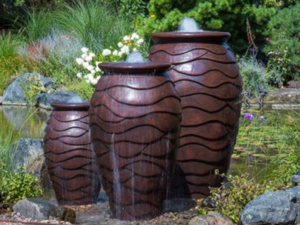 Three decorative water fountains in a lush garden.